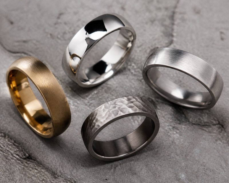 Four men's wedding bands showing matte, polished, brushed and hammered finishes