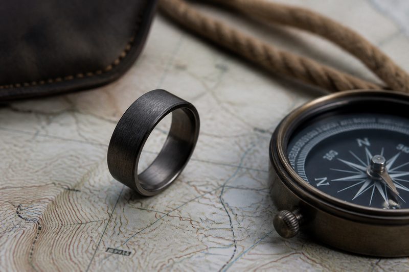 Rugged men's wedding ring on a topographic map beside a compass