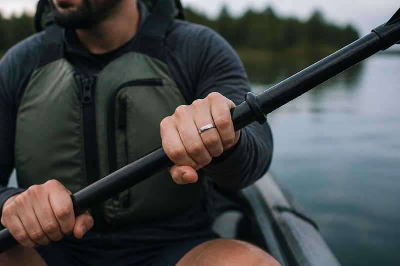 Hands gripping a kayak paddle with a light titanium wedding ring on the ring finger