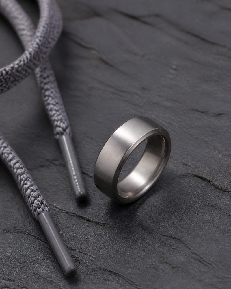 Brushed titanium men's wedding band on dark slate showing its satin finish
