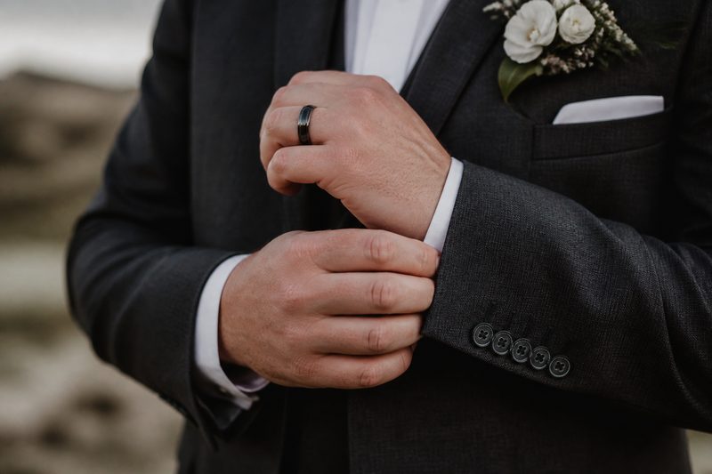 NZ groom adjusting his suit cuff with a dark tungsten wedding band on his hand