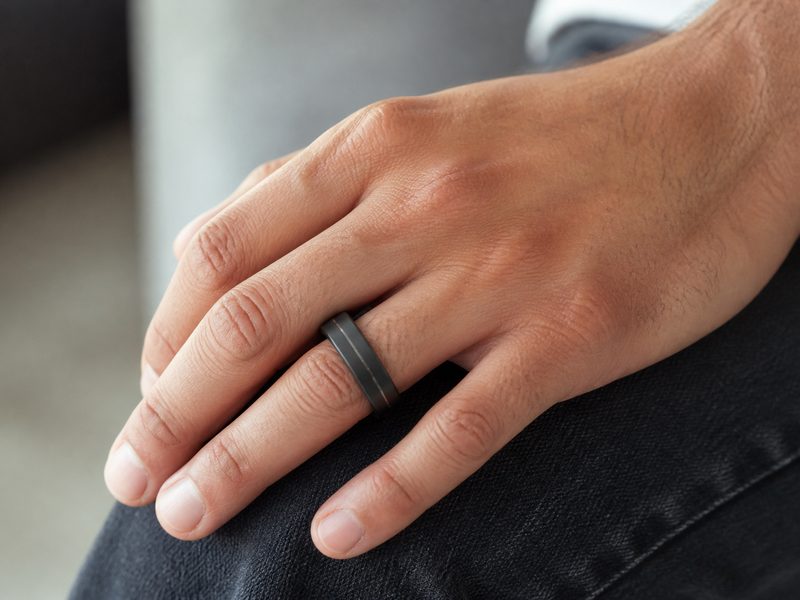 Man's hand wearing a black ring with a contrasting inlay line