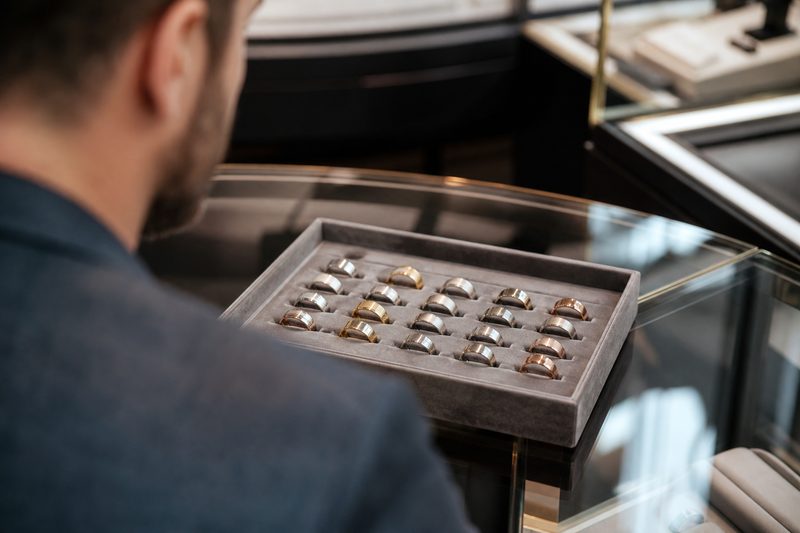 Man viewing a tray of men's wedding rings in different metals at a jewellery counter